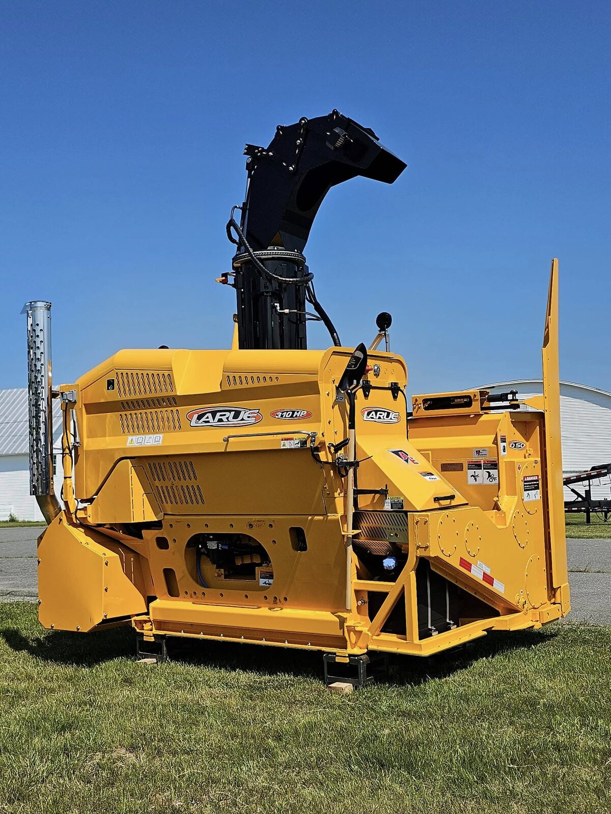 Yellow LaRue 312 HP snow blower with raised black discharge chute, parked on grass